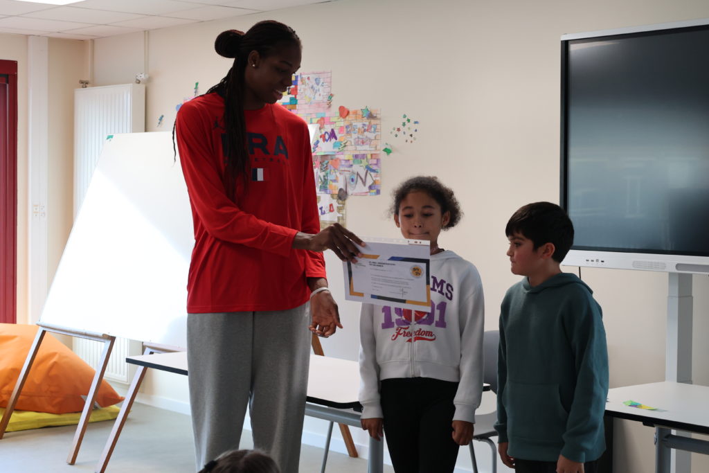 Dominique Malonga remet le diplôme "Génération 2024" à deux élèves de l'école élémentaire Sévigné Paul Bert.
