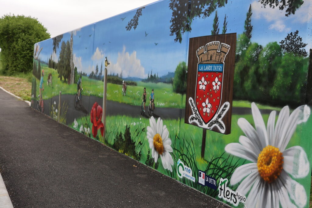 Une fresque a été peinte sur un mur existant qui protège du cours d'eau en contre-bas